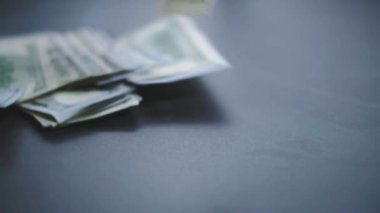Düşen Dolarlar banknotları. Yüksek kaliteli düşen dolar banknotları. Birçok Amerikan doları yavaşça masaya düşüyor. Adam yeşil Amerikan parası saçıyor. Amerikan finans sistemi