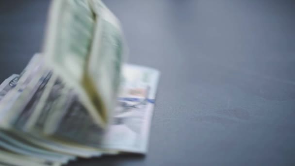 Muchos dólares americanos están cayendo lentamente sobre la mesa. El hombre lanza dinero verde americano. Sistema financiero estadounidense — Vídeos de Stock