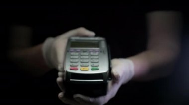 Para transferi için kredi kartı makinesi. Kauçuk eldivenli adamlar NFC terminalini ücretsiz ödeme için tutuyorlar. Elektronik paranın banka hizmetleri. Mali başarı ve güvenlik