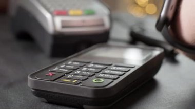 NFC teknolojisi. Alıcı akıllı bir saat kullanarak satın alma ücretini bağlantısız olarak ödüyor. Koronovirüs salgını sırasında cihazla kablosuz ödeme. Küçük işletmeler