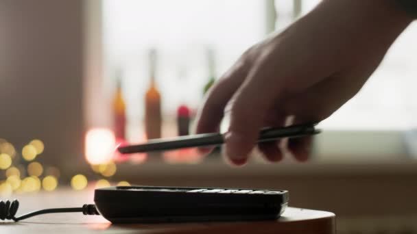 Betaal telefonisch via de contactloze betaalterminal van POS. Een gebruiker doet een aankoop met behulp van een smartphone in een winkel of restaurant. E-geld tegen contant geld portemonnee — Stockvideo