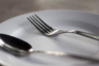 Beyaz masada çatallı boş gümüş tabak..