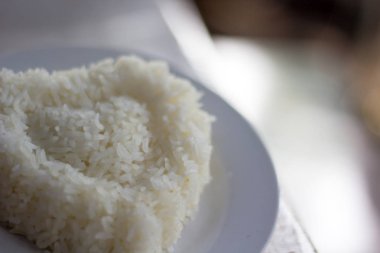 Tahta masada kalp şeklinde beyaz tabakta pirinç.