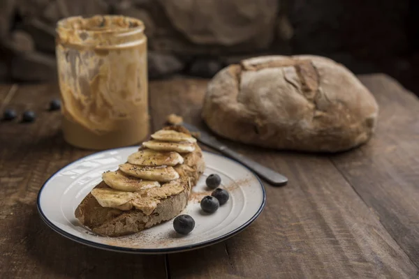 Veganes Frühstück, rustikales Brot mit Erdnussbutter und Banane — Stockfoto