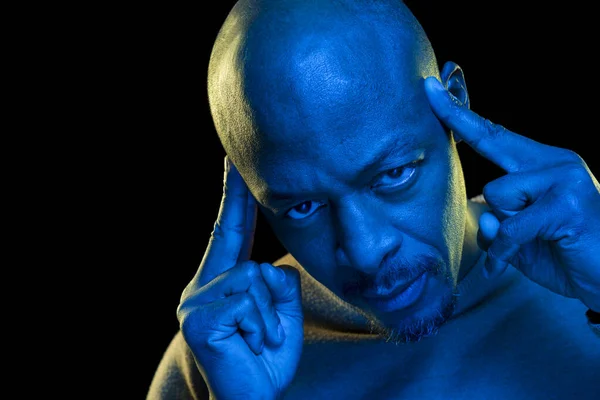 Konsantrasyon ve zihin kavramı. Doymuş mavi jel filtresi ve siyah arka planı olan siyah bir adam.