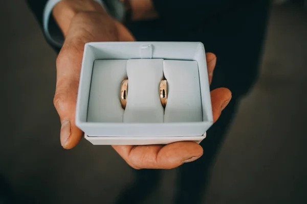 แหวนแต่งงานในกล่องสีขาวในมือของเจ้าบ่าว . — ภาพถ่ายสต็อก