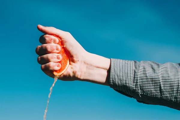 Fresh grapefryit in hand isolated on blue