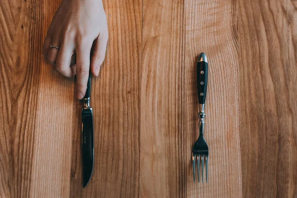 Hand holding fork and knife on wooden background — Stock Photo, Image