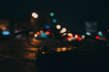 Gece cityscape gökdelenler ve bir çift gözlük görüldüğü gibi şehir ışıkları ile. Bulanık resim.