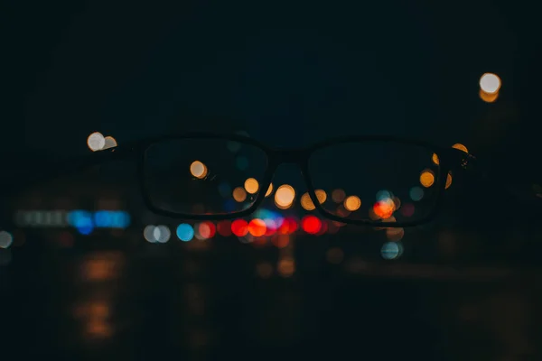 Paisaje nocturno con rascacielos y luces de la ciudad como se ve a través de un par de gafas. Imagen borrosa . —  Fotos de Stock