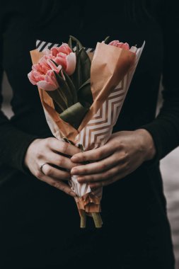 Yumuşak pembe Lale çiçek buketi tutan kadın el kraft kağıt ile dekore edilmiştir.