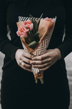 Yumuşak pembe Lale çiçek buketi tutan kadın el kraft kağıt ile dekore edilmiştir.