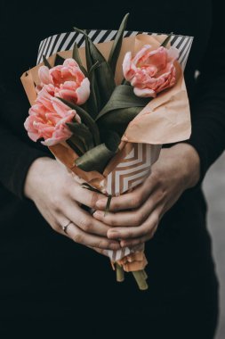 Yumuşak pembe Lale çiçek buketi tutan kadın el kraft kağıt ile dekore edilmiştir.