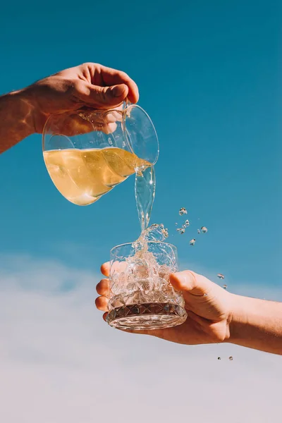 stock image Freash lemonade pouring in a glass with ice with cloud sky background