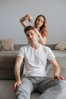 Koronovirüs salgını sırasında kapalı saç kesimi. Eş, kocasına evde saç tıraşında yardım eder.