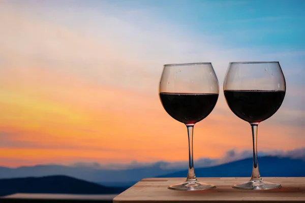 Gün batımına karşı kırmızı şarap kadehleri, gökyüzünde bulutlu kırmızı şarap.