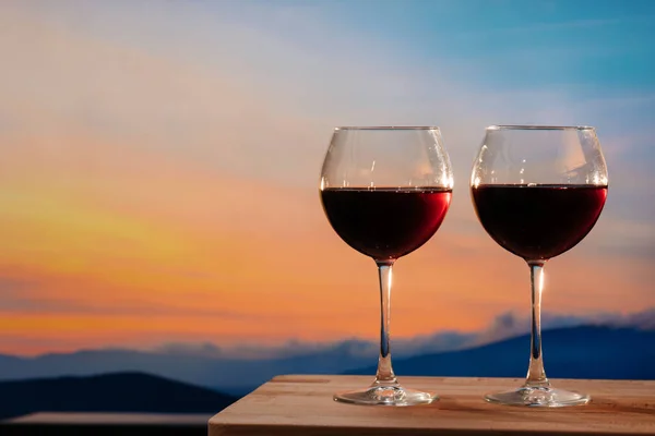Gün batımına karşı kırmızı şarap kadehleri, gökyüzünde bulutlu kırmızı şarap.
