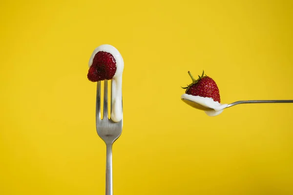 Çilekli ve ekşi kremalı Macro shot. Bir kaşıkta kırmızı böğürtlen. Sarı arkaplan