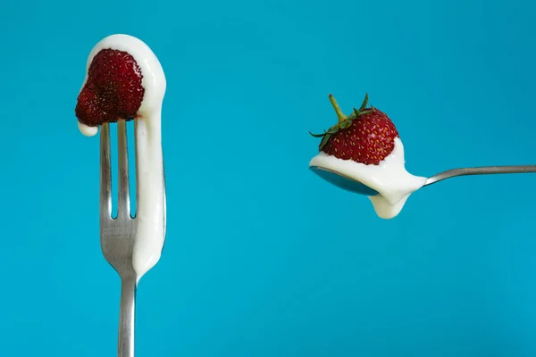 Çilekli ve ekşi kremalı Macro shot. Bir kaşıkta kırmızı böğürtlen. Mavi arkaplan