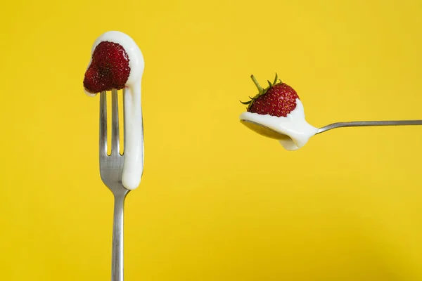 Çilekli ve ekşi kremalı Macro shot. Bir kaşıkta kırmızı böğürtlen. Sarı arkaplan