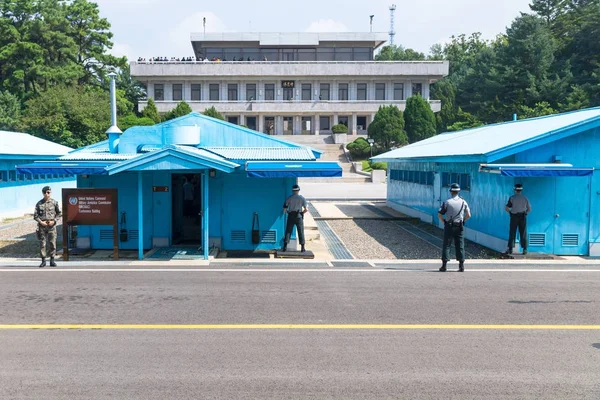 JSA en DMZ, Corea - 8 de septiembre de 2017: Soldados y soldados de la ONU en un día soleado frente a edificios azules en la frontera norcoreana con turistas norcoreanos en el fondo en Korean Demilit —  Fotos de Stock