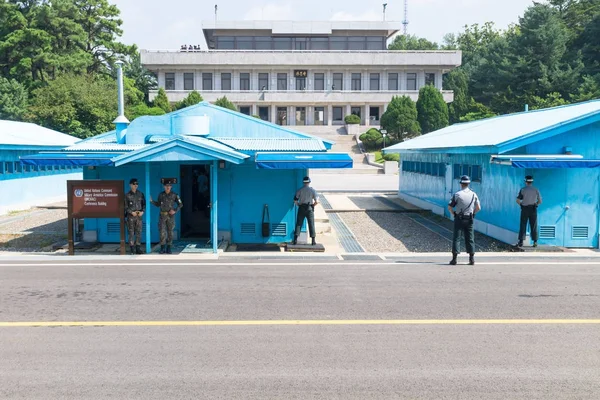 JSA all'interno di DMZ, Corea - 8 settembre 2017: soldati delle Nazioni Unite e 2 soldati con abiti mimetici davanti a edifici blu al confine nordcoreano con i turisti nordcoreani sullo sfondo a Kor — Foto Stock
