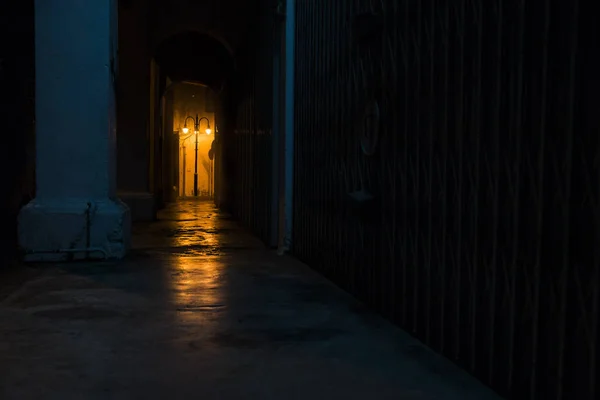 Empty dark street at night with light of latern shining through arches — Stock Photo, Image