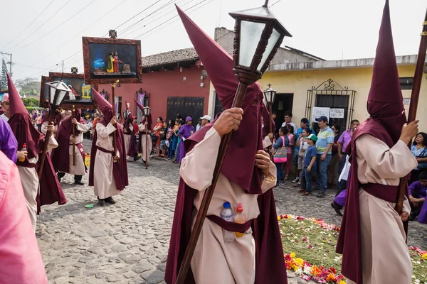 Personas con trajes de capucha puntiaguda llevando pinturas del camino de la cruz en la procesión de San Bartolomé de Becerra, Antigua, Guatemala —  Fotos de Stock