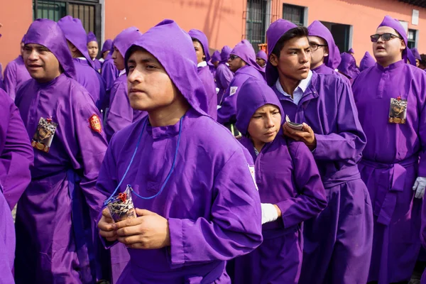 Junge lila gewandete männer, die bei der prozession von san bartolome de becerra in 1a avenida, antigua, guatemala — Stockfoto