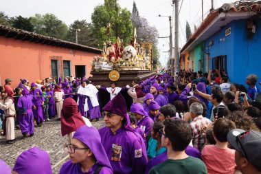 Mor kaftanlı adam San Bartolome de Becerra, Antigua, Guatemala alayı İsa ve bir haç ile bir float taşıyan izlerken ziyaretçi