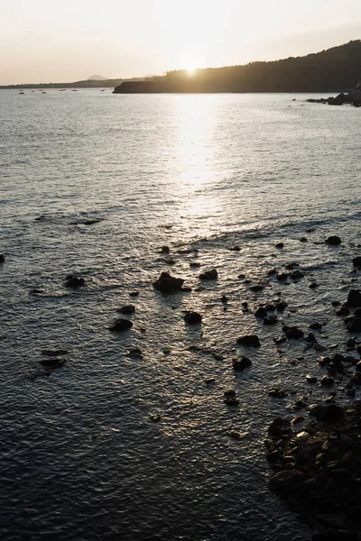 Pôr do sol no oceano com montes e pedras, Seogwipo, Jeju Island, Coreia do Sul — Fotografia de Stock