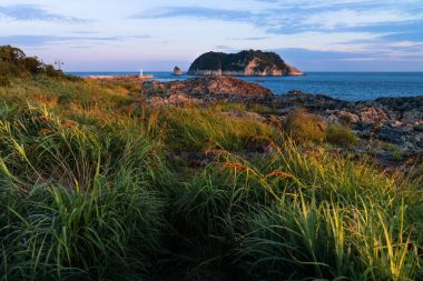 Turuncu ışık manzaralı ay Adası ve deniz feneri günbatımı sırasında Seaseom, Seogwipo, Jeju Adası, Güney Kore