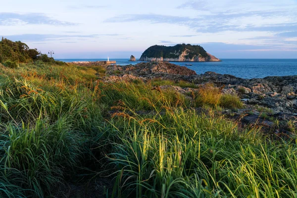 Sunshined grassland and Lighthouse during sunset at Seaseom, Seogwipo, Jeju Island, South Korea — Stock Photo, Image