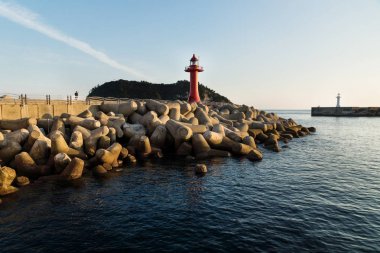 Deniz kenarındaki sete wavebreakers Seogwipo, Jeju Adası, Güney Kore ile deniz feneri, gün batımını izlemek kişi