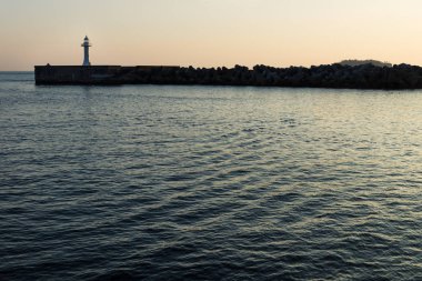 Deniz kenarındaki sete wavebreakers Seogwipo, Jeju Adası, Güney Kore ile Sarı ışıkta ile beyaz deniz feneri