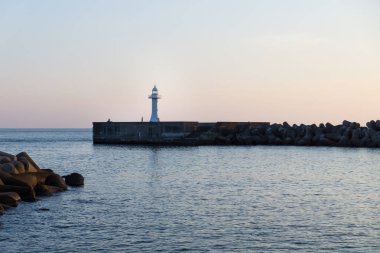 Deniz kenarındaki sete wavebreakers Seogwipo, Jeju Adası, Güney Kore ile deniz feneri boyunca yürüyüş kişi