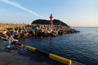 Gün batımı sırasında balıkçı limanı ile kırmızı fener, Seogwipo, Jeju Adası, Güney Kore
