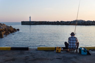 Arkasında balıkçı limanı ile beyaz deniz feneri sırasında günbatımı, Seogwipo, Jeju Adası, Güney Kore