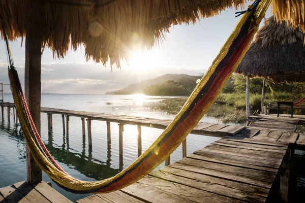 Hamaca en el muelle durante la puesta del sol con rayos de sol en el lago Itza, El Remate, Petén, Guatemala —  Fotos de Stock