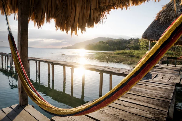 Hamaca en el muelle durante la puesta del sol con haz de sol en el lago Itza, El Remate, Petén, Guatemala —  Fotos de Stock