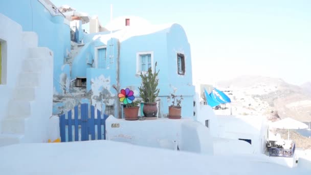 Oia Santorini ギリシャの景色を望む典型的なギリシャの建物の前に動くカラフルな風車 — ストック動画