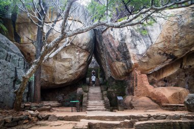 Tourists walking on stairs between two huge stones in Sigiriya, Sri Lanka