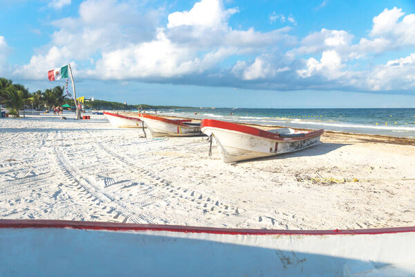 Boats at Playa Pescadores with local floag and blue sky and cloudscape, Tulum, Mexico