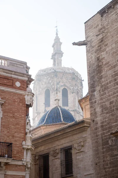 İspanya, Valencia 'daki tarihi evler tarafından çerçevelenmiş katedral kulesi aydınlık