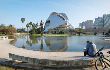 Valencia, Spain - 17 February 2020: Man sitting at pond at Palau des Arts Reina Sofia in the City of Arts and Sciences designed by architects Santiago Calatrava and Felix Candela