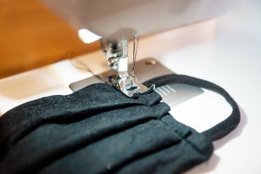 Siyah bir ev yapımı yüz maskesi dikmek Corona virüsüne karşı korunmak için katlanır.