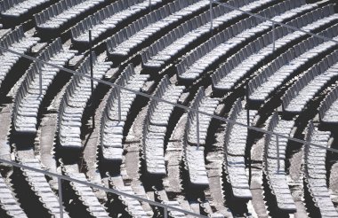 Barcelona, İspanya 'daki Olimpiyat Stadyumu' nun tribününde karlı boş güneşli sandalyeler.