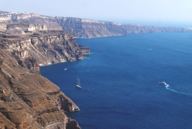 Güneşli bulutsuz bir günde, Fira, Santorini, Yunanistan 'da mavi okyanusa uzanan volkanik yüksek kayalıklar