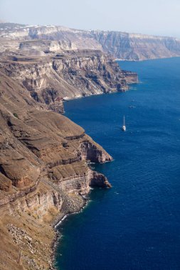 Güneşli bulutsuz bir günde, Fira, Santorini ve Yunanistan 'da mavi okyanusa uzanan volkanik yüksek kayalıklar