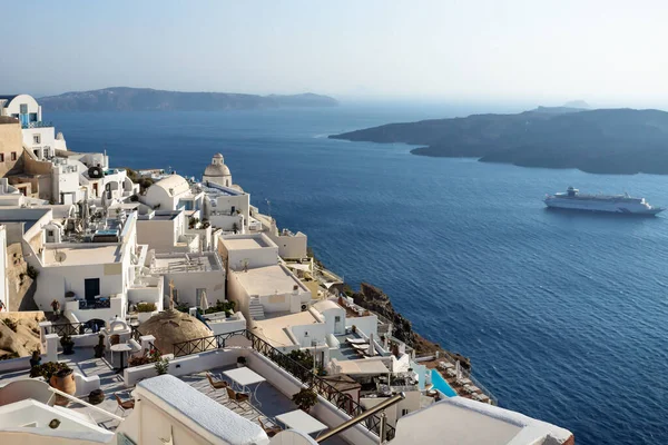 Güneşli bir günde kilise kulesi olan tipik bir Yunan köyü mavi okyanusun üzerinde uzanan ve geçen yolcu gemisi Fira, Santorini, Yunanistan